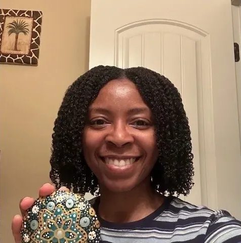 Smiling person holding a decorative item.