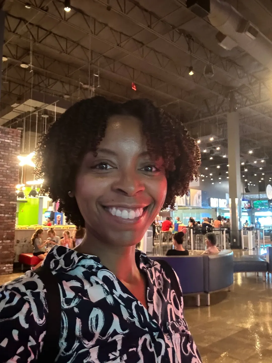 Smiling woman in a lively indoor setting.