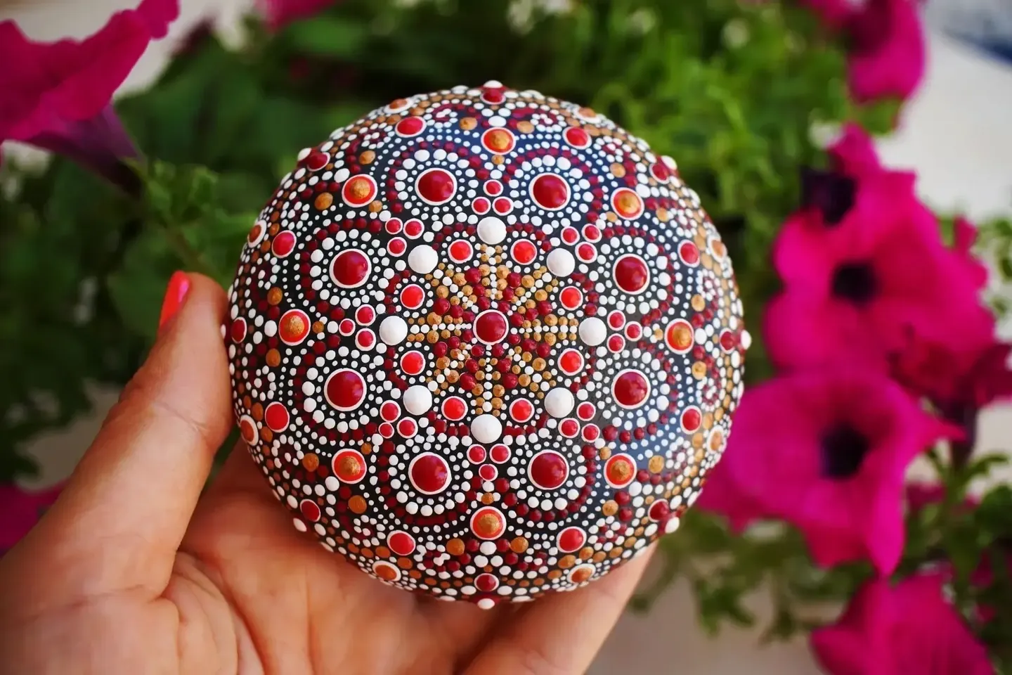 Hand holding a colorful mandala stone outdoors.